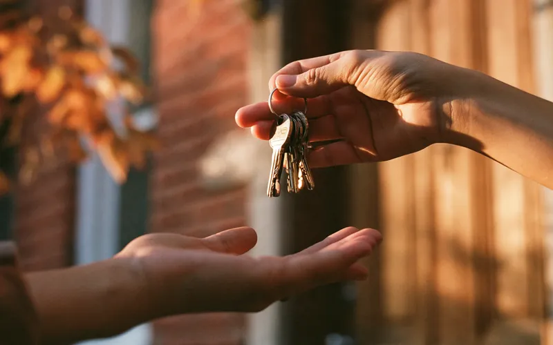 Remise des clés d’une maison devant une porte en bois